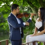 Josué Rugama tocando el violín para su esposa en un puente a la orilla de un lago