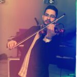 violinista Josué Rugama tocando un violín electroacústico en una fiesta con luces