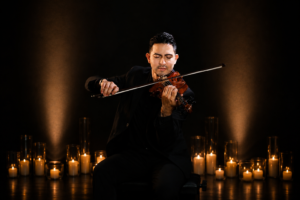 violinista Josue rugama con candelas de fondo candlelights